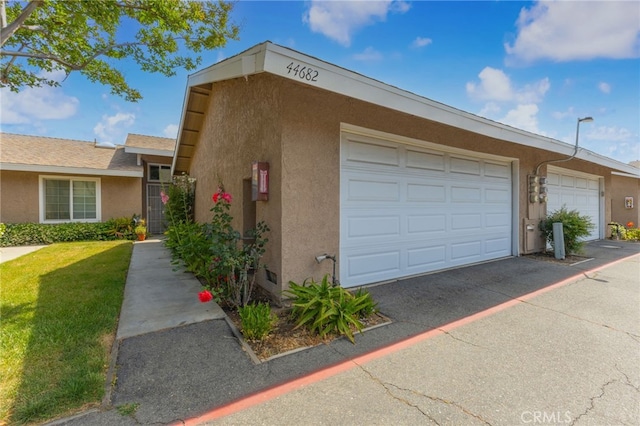 44682 La Paz Rd, Temecula, CA 92592 - view of side of home with stucco siding, a yard, and driveway