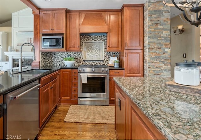 2645 S Patton Ave, San Pedro, CA 90731 - kitchen featuring appliances with stainless steel finishes, custom range hood, wood finished floors, tasteful backsplash, and dark stone counters