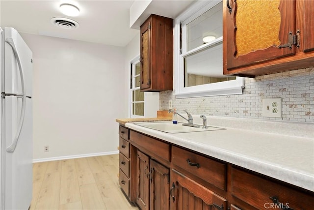 9241 Pali Ave, Tujunga, CA 91042 - kitchen featuring freestanding refrigerator, decorative backsplash, light wood-style flooring, a sink, and baseboards