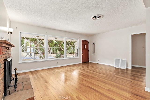9241 Pali Ave, Tujunga, CA 91042 - unfurnished living room featuring a fireplace, a textured ceiling, plenty of natural light, and light wood finished floors