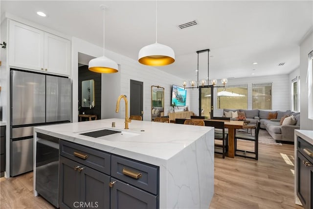 40 Lomada St, Rancho Mission Viejo, CA 92694 - kitchen with freestanding refrigerator, light stone countertops, light wood-style flooring, decorative light fixtures, and a center island with sink