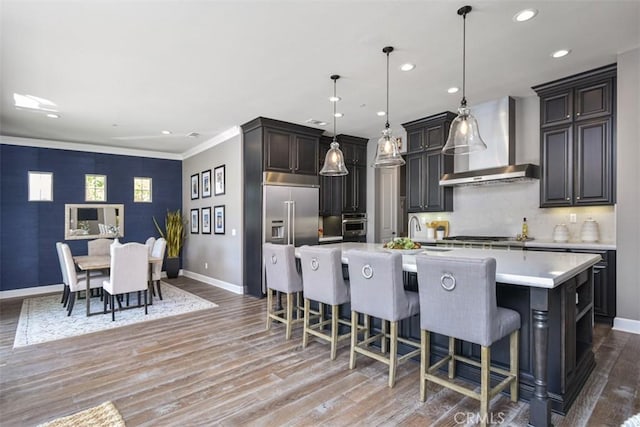 23942 Schoenborn St, West Hills, CA 91304 - kitchen featuring wall chimney exhaust hood, baseboards, light countertops, light wood-type flooring, and a kitchen breakfast bar