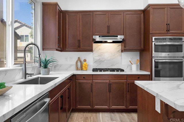 1686 Pember Ave, Chula Vista, CA 91913 - kitchen featuring stainless steel appliances, under cabinet range hood, decorative backsplash, light stone countertops, and light wood-style floors
