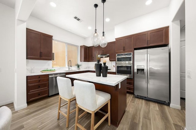 1686 Pember Ave, Chula Vista, CA 91913 - kitchen featuring stainless steel appliances, light wood-type flooring, a center island, pendant lighting, and a kitchen bar