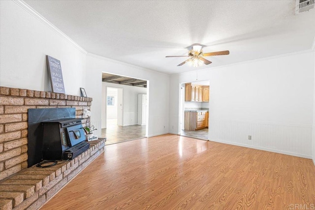 1105 Via Prado, Fallbrook, CA 92028 - unfurnished living room with a ceiling fan, light wood-style flooring, crown molding, a wood stove, and a wainscoted wall