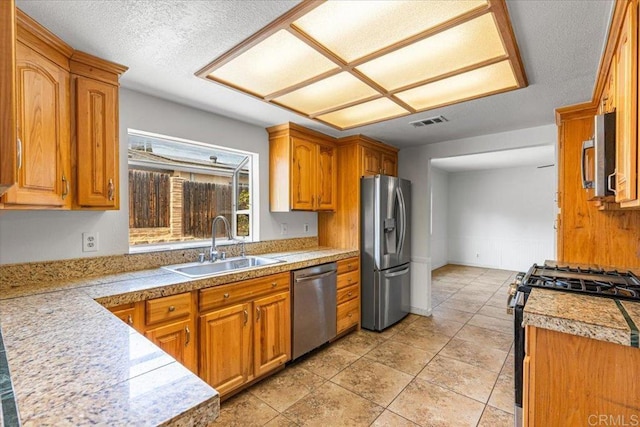 1105 Via Prado, Fallbrook, CA 92028 - kitchen featuring appliances with stainless steel finishes, a sink, tile counters, brown cabinetry, and a textured ceiling