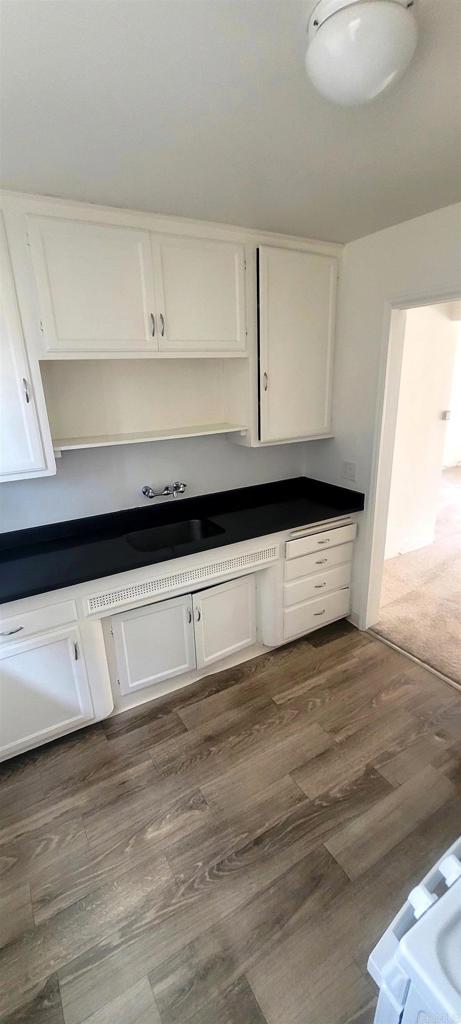 481848321/2 Palm Ave, La Mesa, CA 91942 - kitchen with white cabinetry, a sink, dark countertops, dark wood finished floors, and open shelves