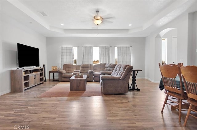12233 Pueblo Trl, Phelan, CA 92371 - living area featuring a raised ceiling, arched walkways, wood finished floors, baseboards, and ceiling fan