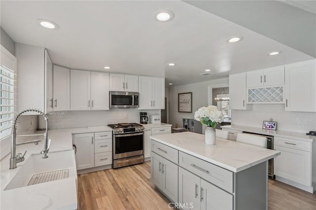 1926 N Vallejo Way, Upland, CA 91784 - kitchen featuring appliances with stainless steel finishes, a sink, decorative backsplash, light stone countertops, and light wood-type flooring