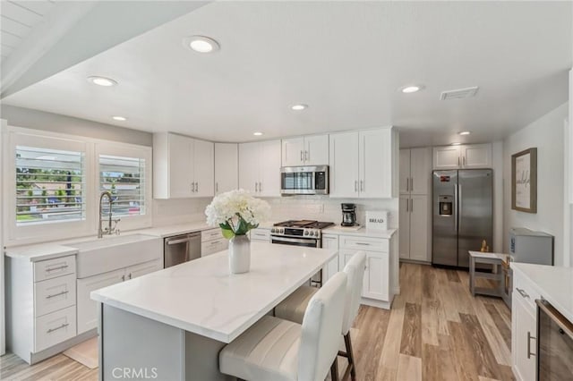 1926 N Vallejo Way, Upland, CA 91784 - kitchen with appliances with stainless steel finishes, a sink, a kitchen island, light wood-style floors, and wine cooler