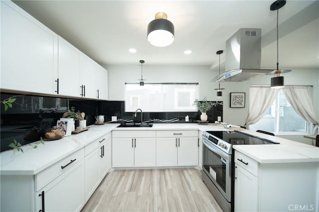 921 W 19th St, Merced, CA 95340 - kitchen featuring stainless steel electric range oven, island exhaust hood, a peninsula, decorative backsplash, and plenty of natural light