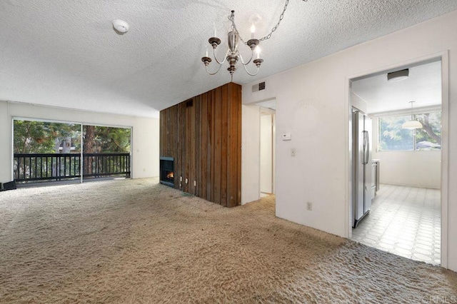 3213 Raintree Cir, Culver City, CA 90230 - unfurnished living room with a chandelier, plenty of natural light, light colored carpet, a textured ceiling, and wood walls