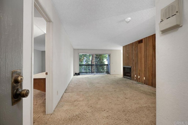 3213 Raintree Cir, Culver City, CA 90230 - unfurnished living room with carpet floors, wooden walls, a fireplace, a textured ceiling, and a wall mounted AC
