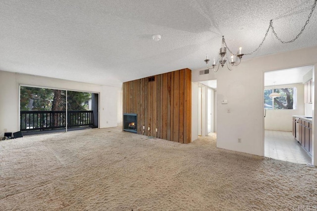 3213 Raintree Cir, Culver City, CA 90230 - unfurnished living room with a chandelier, a warm lit fireplace, carpet, a textured ceiling, and wood walls