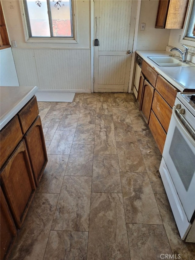 7887 Kempster Ave, Fontana, CA 92336 - kitchen with white gas range, stainless steel dishwasher, wainscoting, light countertops, and brown cabinetry