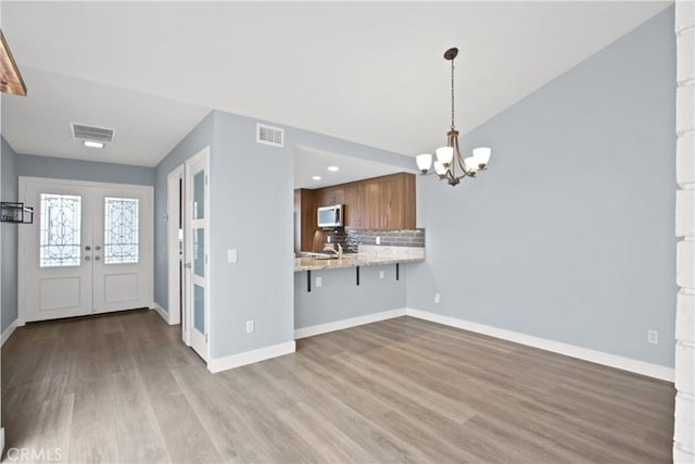 3520 Paseo Flamenco, San Clemente, CA 92672 - kitchen featuring white microwave, a chandelier, french doors, wood finished floors, and brown cabinetry