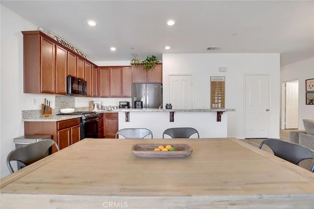 18026 Crabapple Ct, San Bernardino, CA 92407 - kitchen with stainless steel appliances, a breakfast bar area, a center island with sink, recessed lighting, and light stone counters