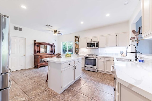 38260 Willow Ct, Murrieta, CA 92562 - kitchen featuring appliances with stainless steel finishes, a ceiling fan, white cabinets, a kitchen island, and a sink