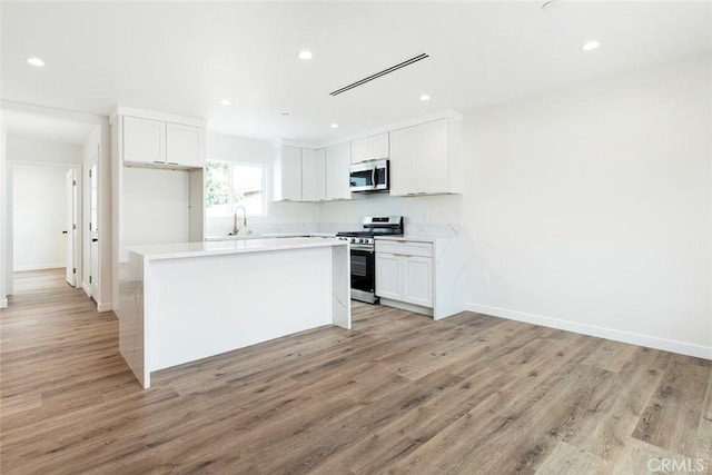 13934 Filmore St, Pacoima, CA 91331 - kitchen featuring stainless steel appliances, light wood finished floors, white cabinets, light countertops, and recessed lighting