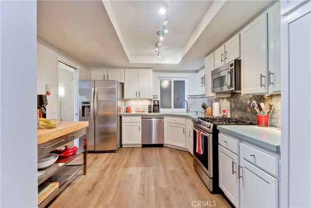 2032 E Bermuda St Unit 103, Long Beach, CA 90814 - kitchen featuring stainless steel appliances, a tray ceiling, a sink, light countertops, and white cabinetry