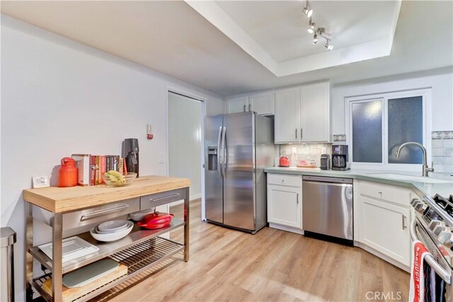2032 E Bermuda St Unit 103, Long Beach, CA 90814 - kitchen featuring appliances with stainless steel finishes, a tray ceiling, decorative backsplash, and a sink