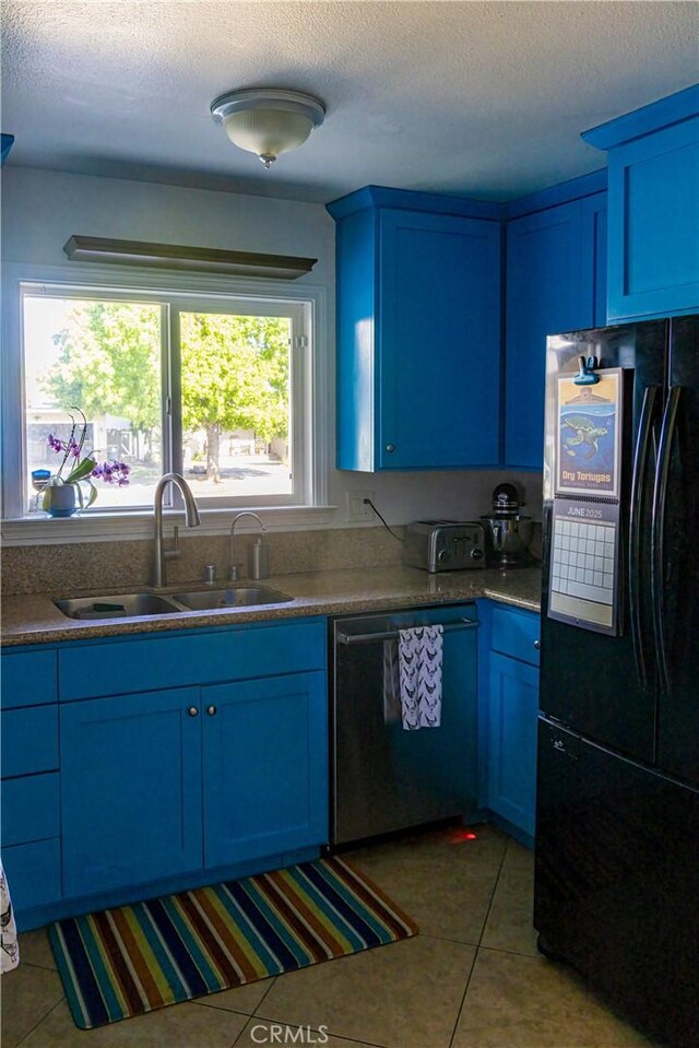 3158 Erie Ave, Merced, CA 95340 - kitchen featuring freestanding refrigerator, dishwasher, blue cabinetry, a sink, and a textured ceiling