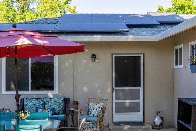 3158 Erie Ave, Merced, CA 95340 - doorway to property featuring stucco siding, roof mounted solar panels, and roof with shingles