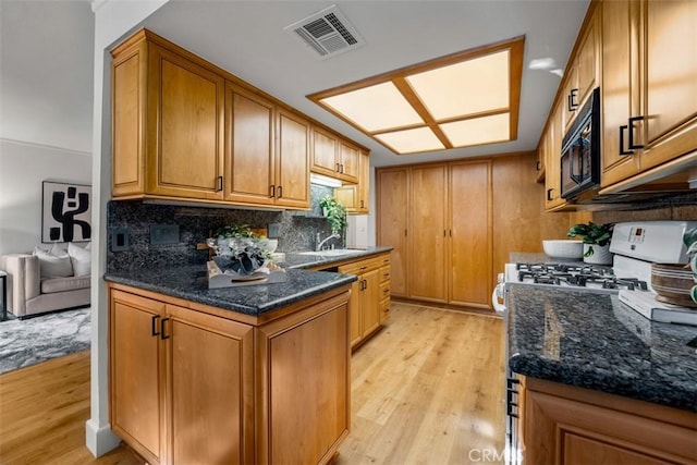 922 N Redding Way Unit E, Upland, CA 91786 - kitchen featuring black microwave, light wood-style flooring, white stove, backsplash, and brown cabinetry