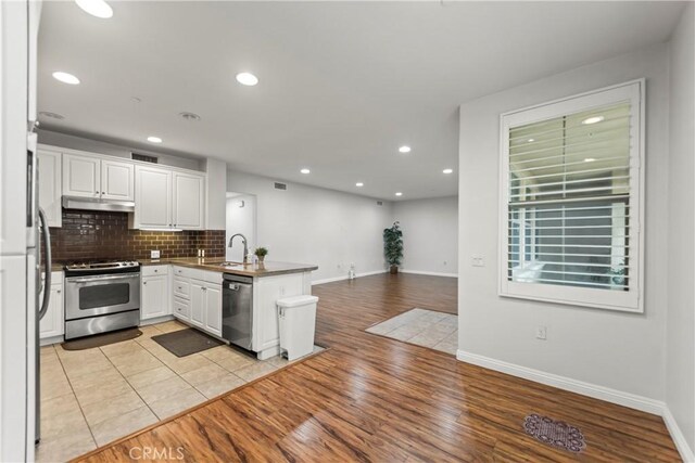 76 City Stroll, Irvine, CA 92620 - kitchen featuring appliances with stainless steel finishes, a sink, a peninsula, under cabinet range hood, and white cabinetry