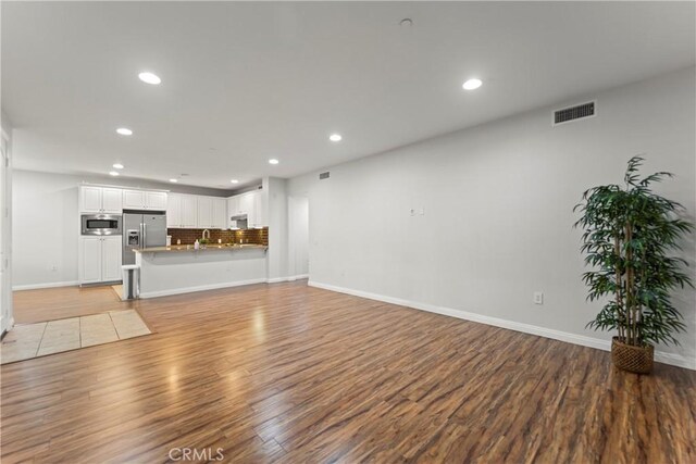 76 City Stroll, Irvine, CA 92620 - unfurnished living room with light wood finished floors, recessed lighting, baseboards, and a sink