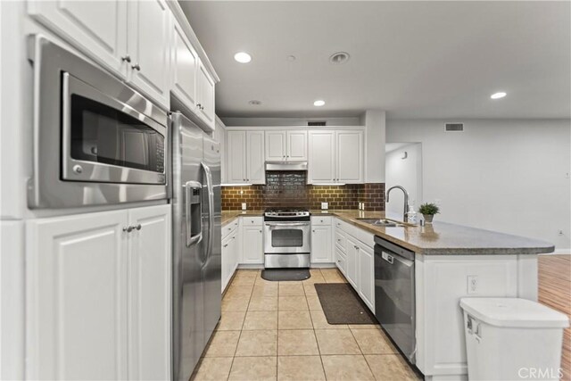 76 City Stroll, Irvine, CA 92620 - kitchen featuring appliances with stainless steel finishes, a sink, a peninsula, under cabinet range hood, and white cabinets