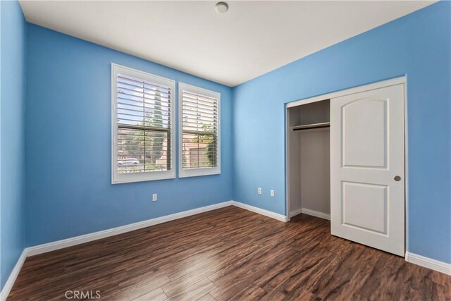 76 City Stroll, Irvine, CA 92620 - unfurnished bedroom with dark wood-style flooring, baseboards, and a closet