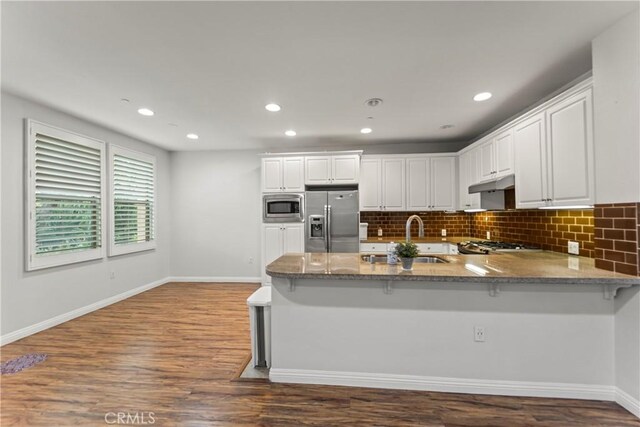 76 City Stroll, Irvine, CA 92620 - kitchen featuring appliances with stainless steel finishes, under cabinet range hood, a sink, stone countertops, and white cabinetry