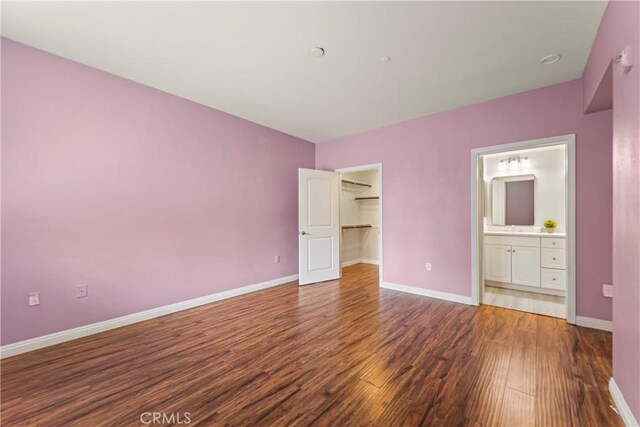 76 City Stroll, Irvine, CA 92620 - unfurnished bedroom with wood finished floors, baseboards, a spacious closet, a closet, and ensuite bath