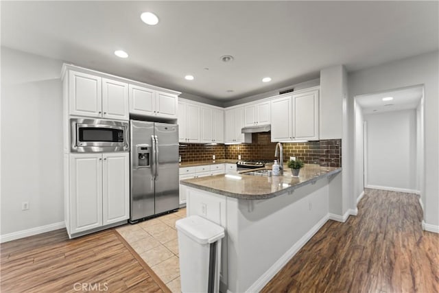 76 City Stroll, Irvine, CA 92620 - kitchen featuring stainless steel appliances, a sink, under cabinet range hood, a peninsula, and white cabinetry