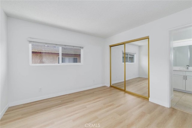 12105 Ramona Blvd, El Monte, CA 91732 - unfurnished bedroom with light wood-style floors, a closet, baseboards, connected bathroom, and a textured ceiling