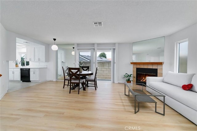 12105 Ramona Blvd, El Monte, CA 91732 - dining space with light wood-type flooring, healthy amount of natural light, a tiled fireplace, a textured ceiling, and baseboards
