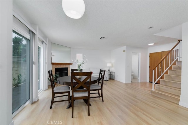 12105 Ramona Blvd, El Monte, CA 91732 - dining space with light wood finished floors, a textured ceiling, stairs, and a fireplace