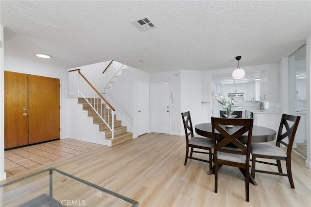 12105 Ramona Blvd, El Monte, CA 91732 - dining space featuring a textured ceiling, light wood-style floors, and stairway