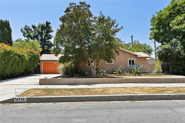 18770 Community St, Northridge, CA 91324 - obstructed view of property featuring driveway, an attached garage, and stucco siding