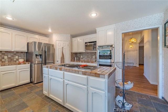 2020 Station Ave, Atwater, CA 95301 - kitchen with appliances with stainless steel finishes, tile countertops, white cabinets, wallpapered walls, and decorative backsplash