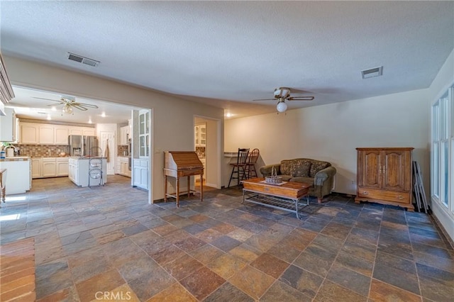 2020 Station Ave, Atwater, CA 95301 - living area featuring ceiling fan, stone tile floors, a textured ceiling, and baseboards