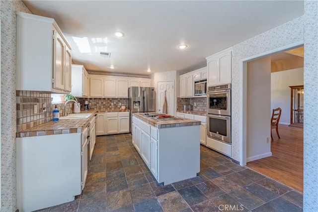 2020 Station Ave, Atwater, CA 95301 - kitchen featuring a sink, appliances with stainless steel finishes, tile counters, decorative backsplash, and white cabinets