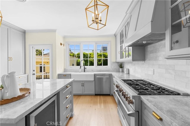 827 Hauser Blvd, Los Angeles, CA 90036 - kitchen featuring stainless steel appliances, gray cabinetry, custom exhaust hood, a sink, and ornamental molding