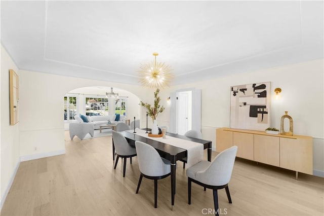 827 Hauser Blvd, Los Angeles, CA 90036 - dining area featuring a chandelier, arched walkways, light wood-style flooring, and baseboards