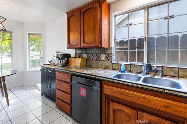 3576 San Jose Ave, Merced, CA 95348 - kitchen with black dishwasher, tasteful backsplash, a sink, brown cabinets, and tile counters