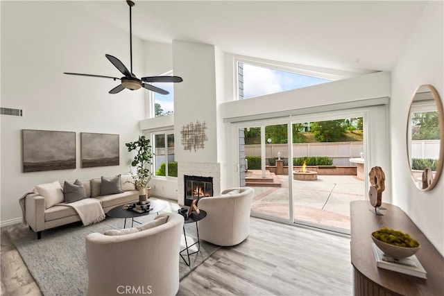 21592 Fernbrook Unit 195, Mission Viejo, CA 92692 - living room with plenty of natural light, wood finished floors, a glass covered fireplace, ceiling fan, and high vaulted ceiling