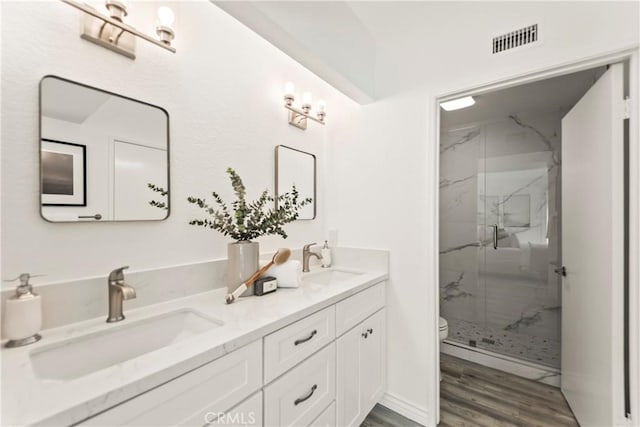 21592 Fernbrook Unit 195, Mission Viejo, CA 92692 - bathroom featuring a marble finish shower, double vanity, toilet, and wood finished floors