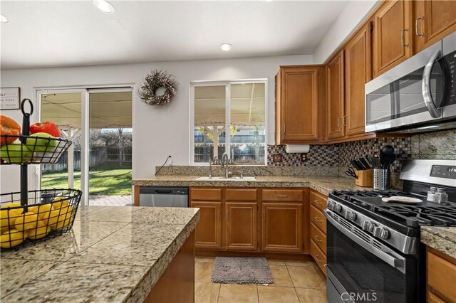 28867 Glencoe Ln, Menifee, CA 92584 - kitchen featuring appliances with stainless steel finishes, a sink, tile counters, brown cabinetry, and tasteful backsplash