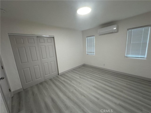 4300 Bancroft Dr, La Mesa, CA 91941 - unfurnished bedroom with wood finished floors, an AC wall unit, a closet, and baseboards